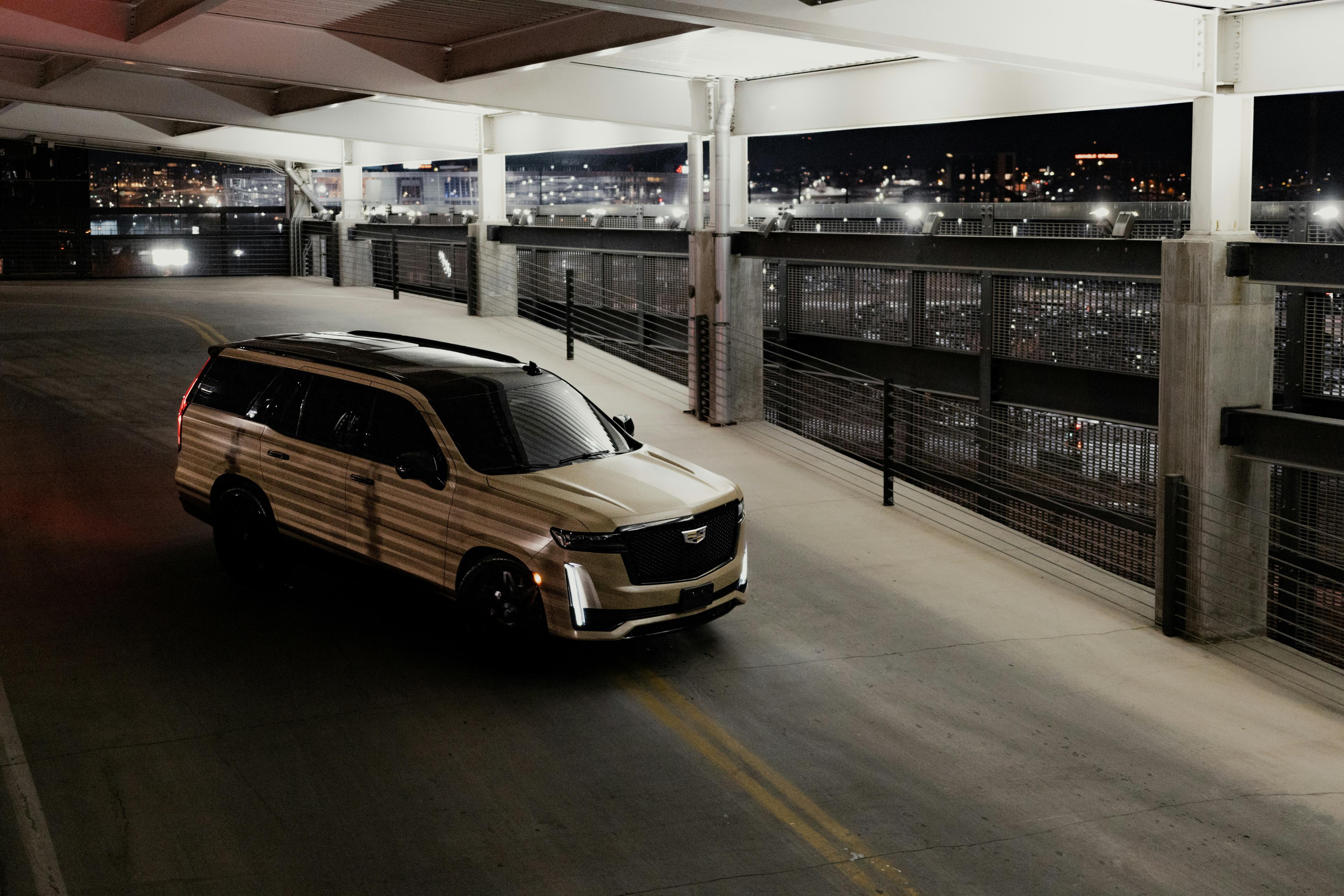 Black Cadillac Escalade SUV parked on the Las Vegas Strip at night with neon lights reflecting